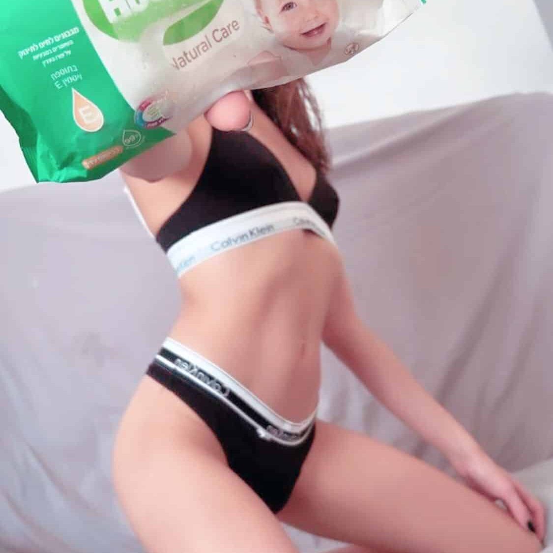 אישה בלבוש תחתון מחזיקה חבילת מגבונים לחים של הוגיס.