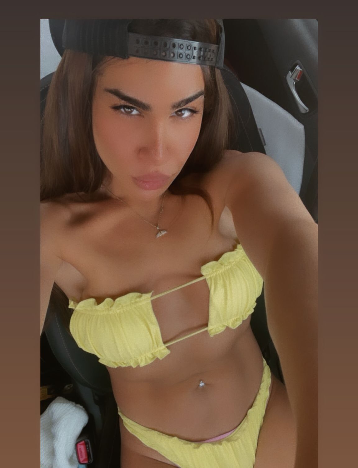 אדם לובש בגדי ים צהובים יושב ברכב וחובש כובע מצחייה הפוך.