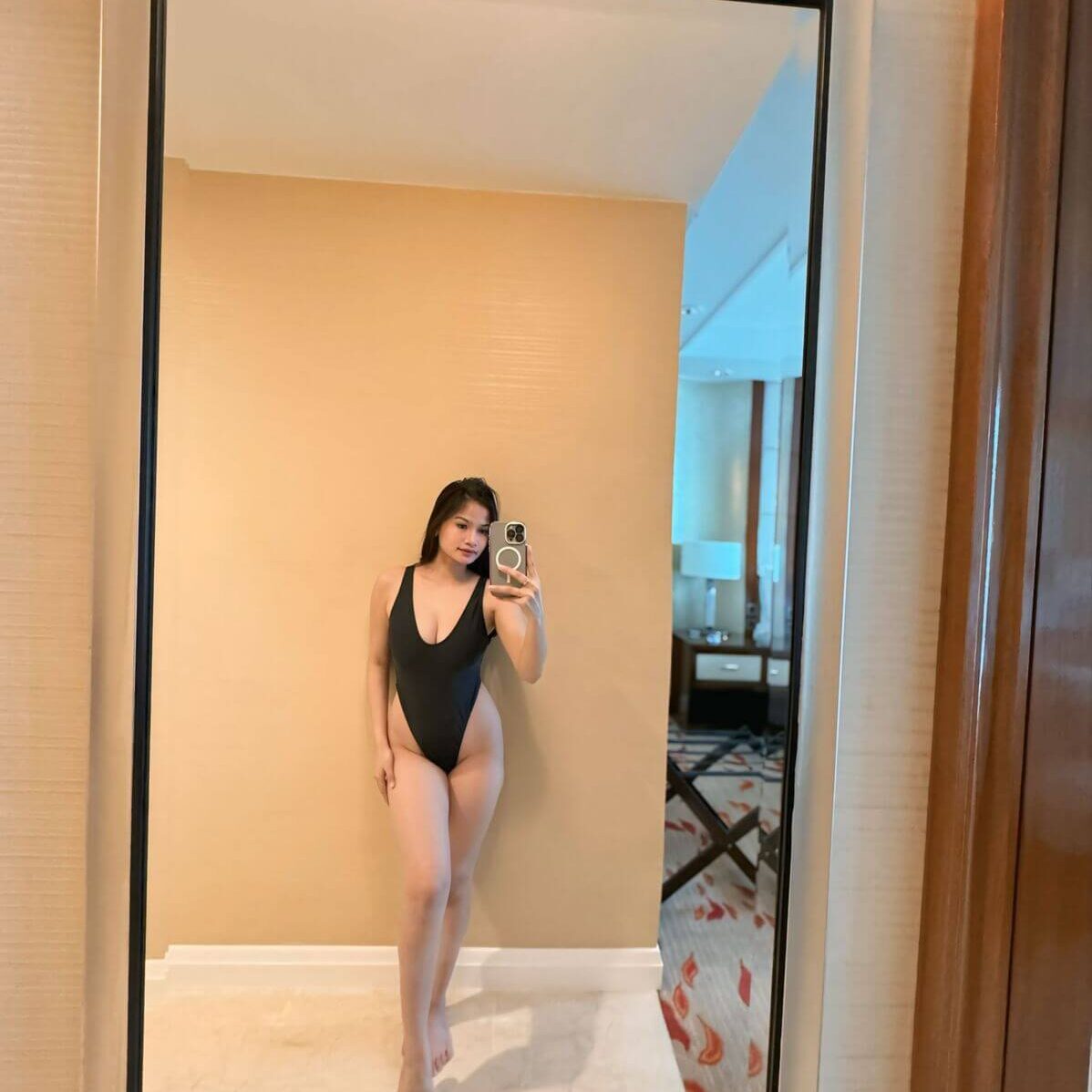 אדם עומד מול מראה ומצלם את עצמו בחליפת שחייה שחורה.