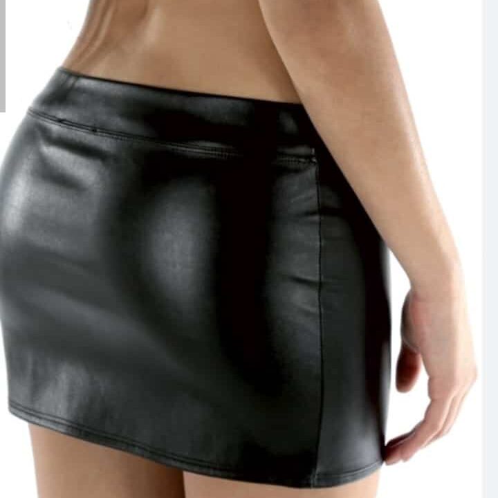 אישה לובשת חצאית מיני שחורה ומחומר מבריק, מצולמת מאחור בחלקה התחתון של הגוף.