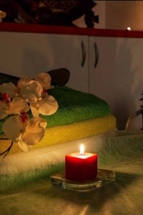 WhatsApp-Image-2024-12-23-at-11.50.19 חדר ספא עם מגבות מקופלות, פרחי סחלב ונרות דולקים ליצירת אווירה רגועה.