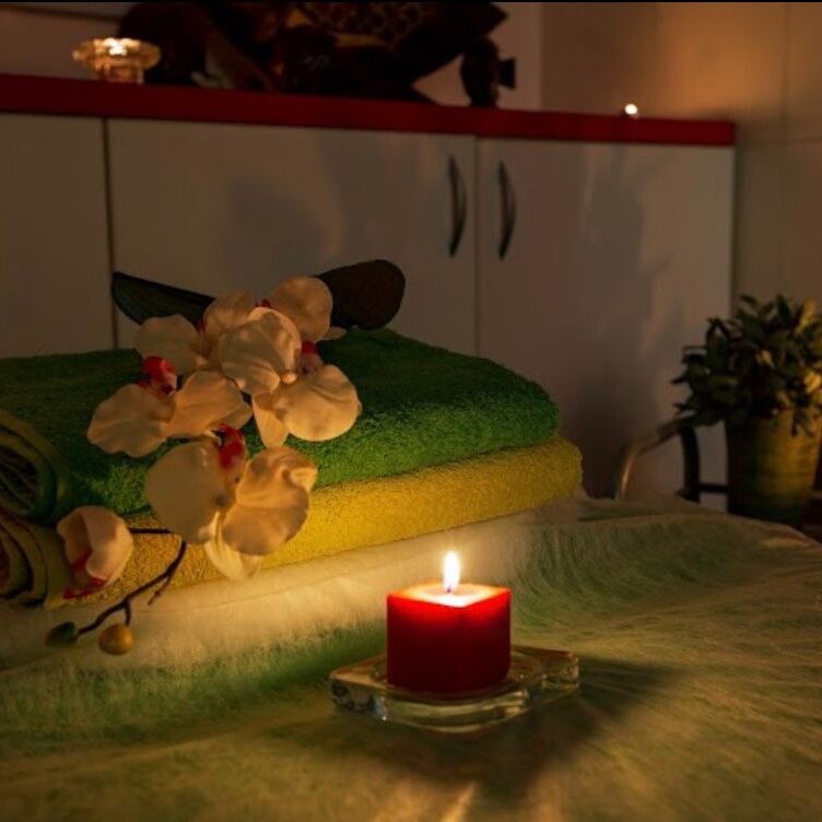 חדר ספא עם מגבות מקופלות, פרחי סחלב ונרות דולקים ליצירת אווירה רגועה.