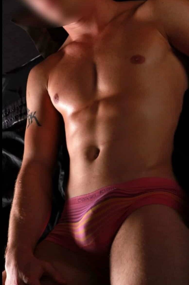 WhatsApp-Image-2025-01-21-at-12.23.15-1 גבר חסר חולצה עם פרצוף מטושטש, לובש תחתונים צבעוניים, עם קעקוע על זרועו.