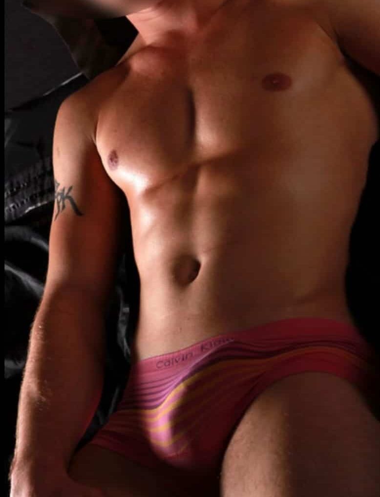 WhatsApp-Image-2025-01-21-at-12.23.15-1 גבר חסר חולצה עם פרצוף מטושטש, לובש תחתונים צבעוניים, עם קעקוע על זרועו.