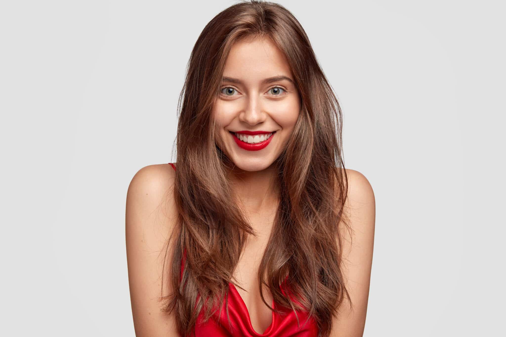 beauty-fashion-makeup-people-concept-lovely-happy-woman-with-red-lipstick-shows-white-perfect-teeth-has-healthy-skin-long-dark-hair-isolated-white-wall-expresses-happiness-scaled-1 נערות ליווי